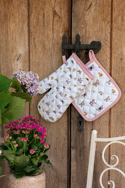 A metal wall hook with a butterfly-themed oven mitt and butterfly-themed pot holder