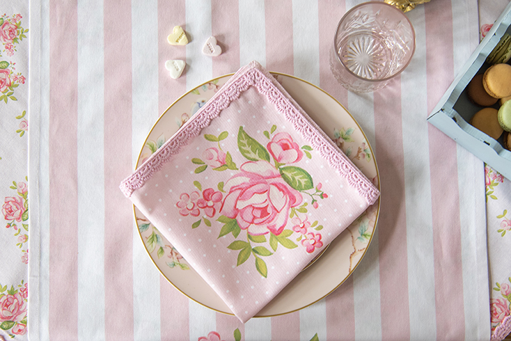 Een romantische roze stoffen servet met een kantje op een high tea bord