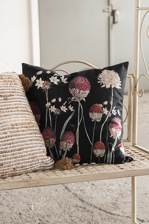 Un cuscino decorativo con motivo floreale su una panca da giardino bianca