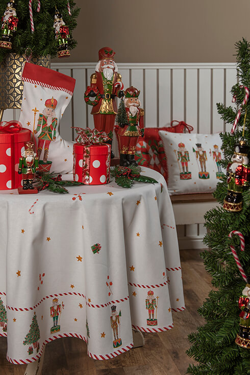 A white Christmas tablecloth with red presents, nutcrackers, and a Christmas stocking