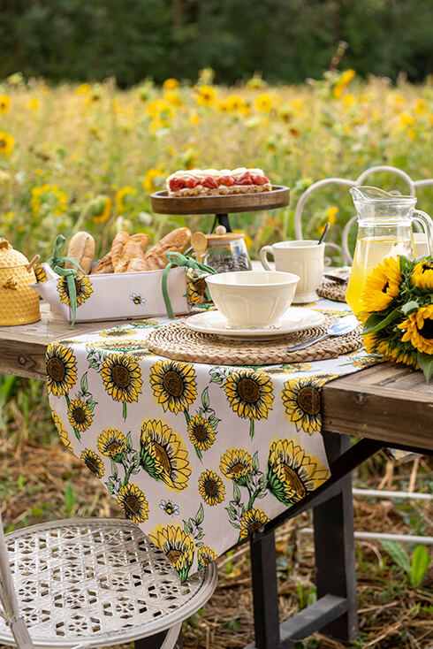 Ein gedeckter Tisch im Garten mit Sonnenblumenmotiv; ein Sonnenblumen-Tischläufer und ein Sonnenblumen-Brotkorb