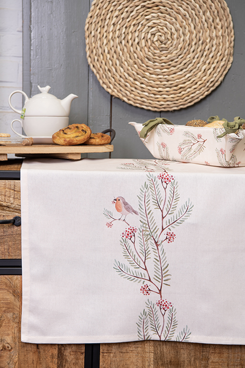 A white table runner with branches, berries, and a robin