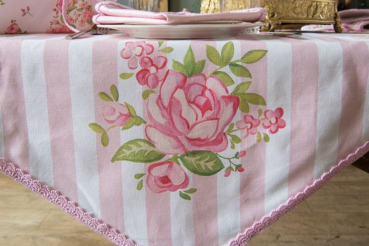 A romantic rose-patterned table runner with a pink lace edge
