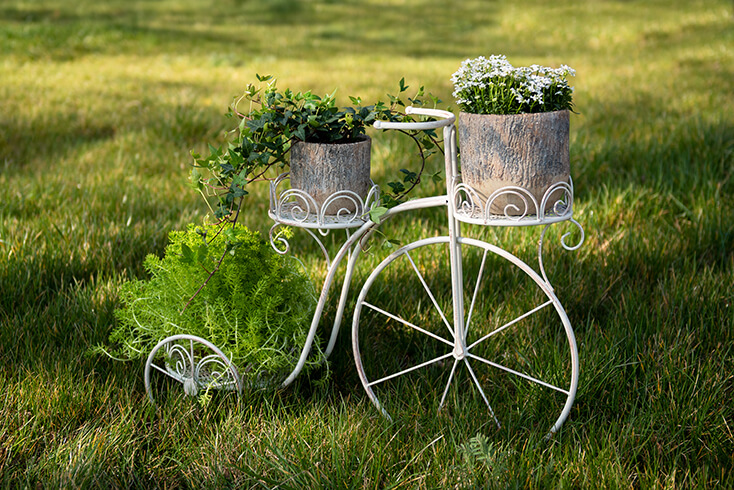 Un support de plante pour vélo blanc avec des pots de fleurs en pierre à l'intérieur