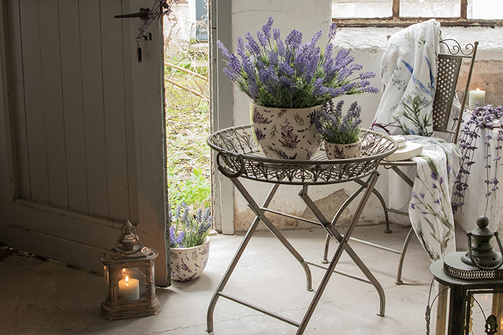 Eine romantische Scheune mit einem Eisen-Pflanzenhalter und zwei Lavendeltöpfen mit Lavendel darin