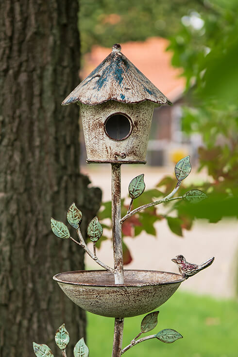 A metal garden stake with a birdhouse and bird bath