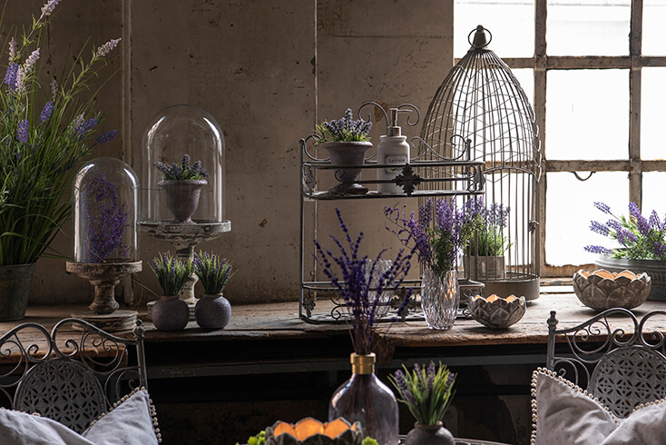 A romantic barn with an iron birdcage, garden decorations, and flower pots