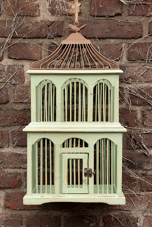 Una gabbia per uccelli in legno verde con tetto in ghisa