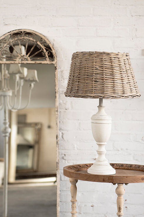 A white lamp base with a wicker lampshade