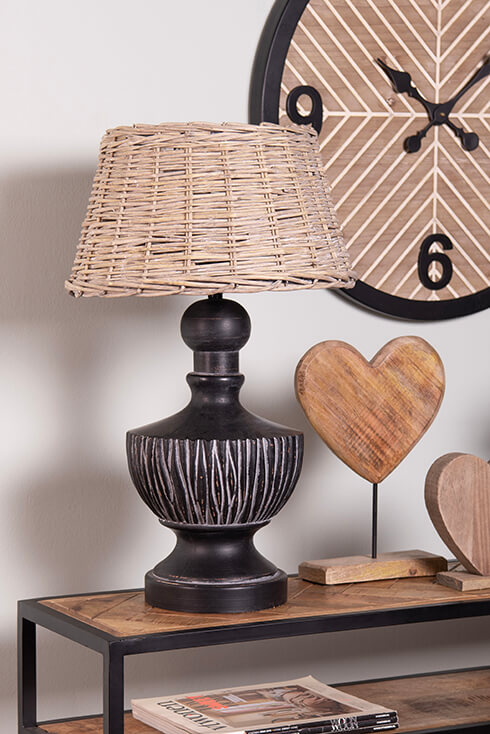 An industrial wall table with wooden hearts, black lamp base with a wicker lampshade