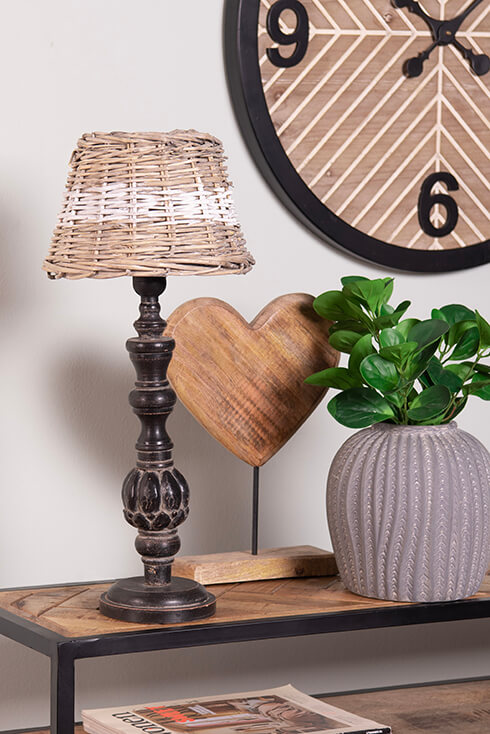 A black lamp base with a wicker lampshade and a grey flower pot