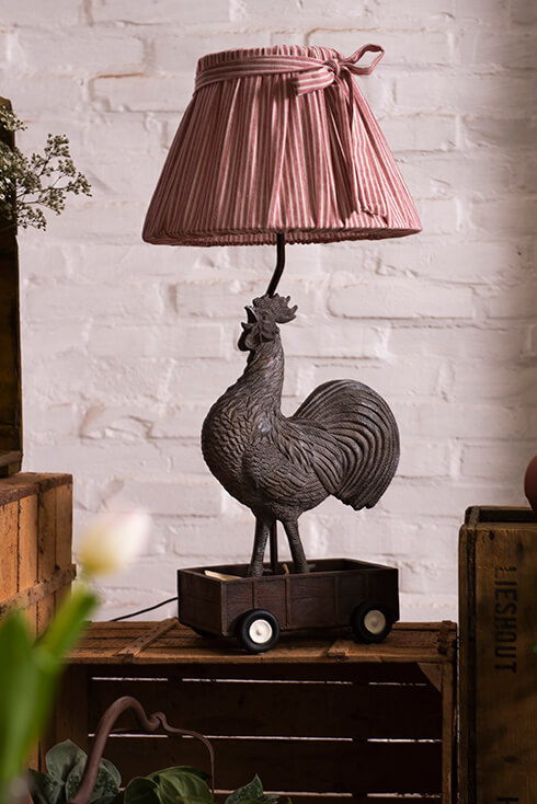 A rooster lamp base with a red fabric lampshade