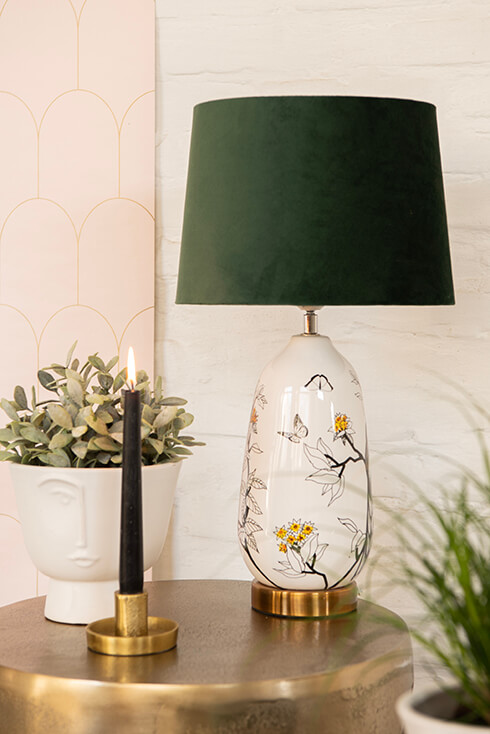 A modern interior with a white flower pot, gold candle holder, and a modern table lamp