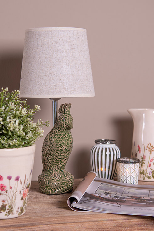 A green bird-shaped lamp with a linen lampshade and two black-and-white tea light holders