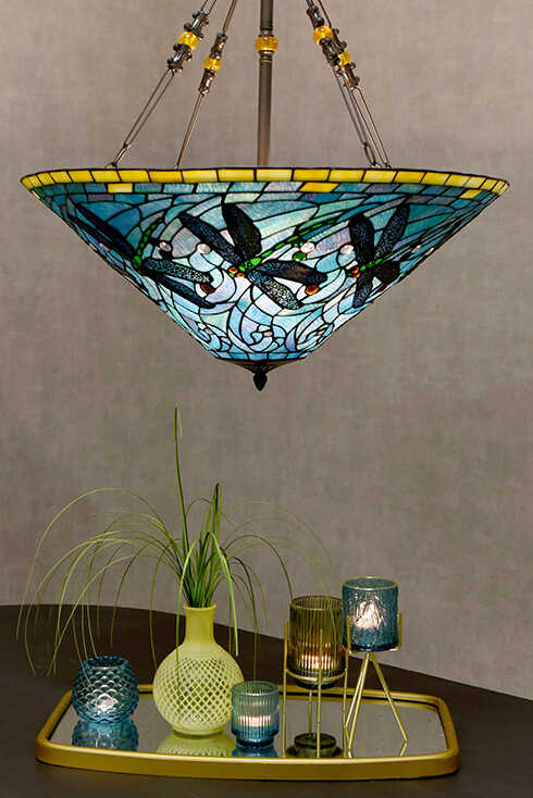 Un grand luminaire suspendu Tiffany avec des couleurs bleues et des libellules vertes, le rebord fini avec du verre jaune