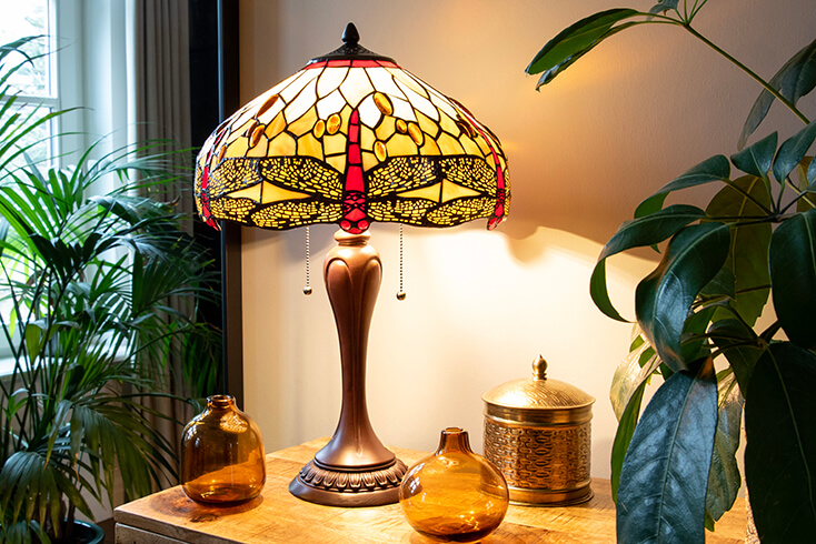 A brown Tiffany table lamp with a yellow lampshade featuring the classic dragonfly