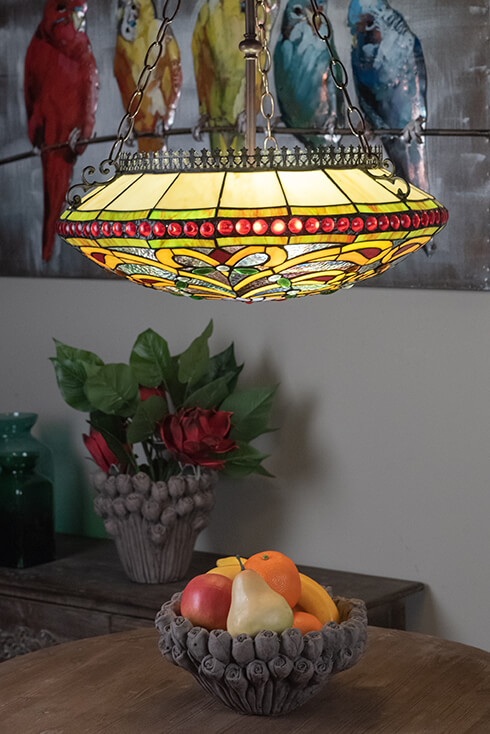 Una grande e colorata lampada a soffitto Tiffany sopra un tavolo da pranzo