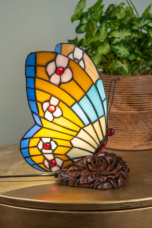 A butterfly Tiffany table lamp with yellow and blue wings featuring flowers
