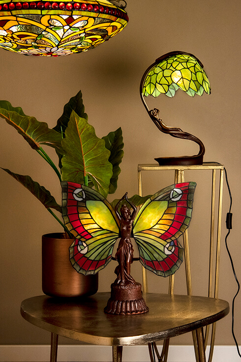 Due lampade da tavolo Tiffany, di cui una rappresenta una donna con ali di vetro colorato