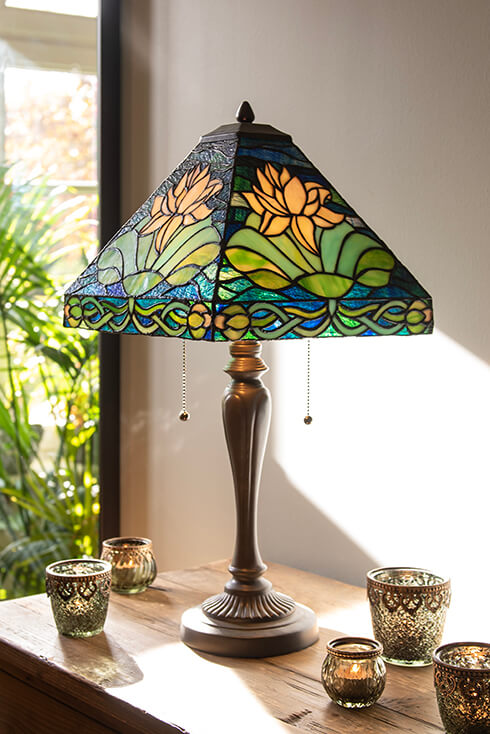 Una lampada da tavolo Tiffany con un paralume a forma di piramide con ninfee sopra