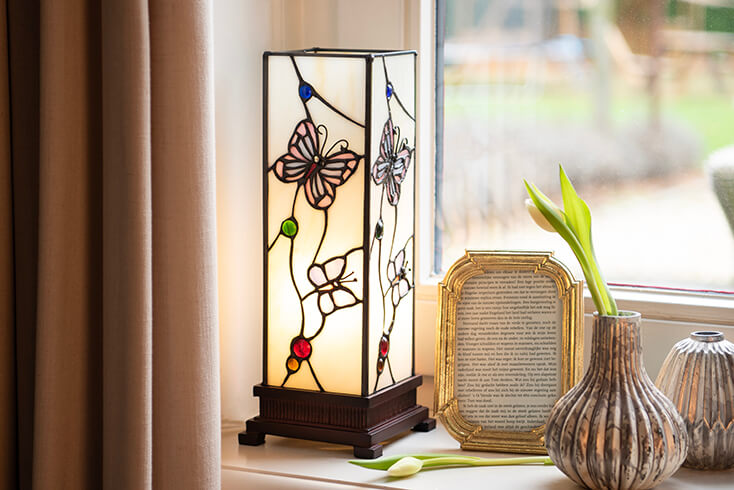 Een Tiffany tafellamp met vlinders en een goudkleurige fotolijst