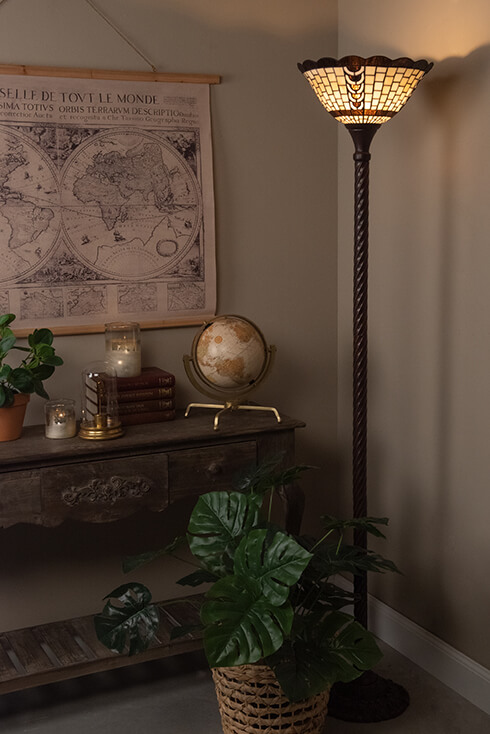 A vintage Tiffany table lamp next to a console table with a map on the wall
