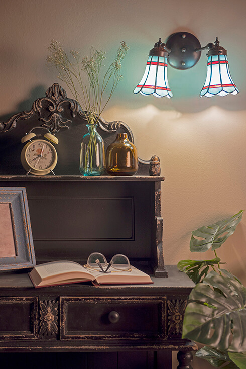 Una scrivania con una lampada da parete in vetro colorato di un colore azzurro tenue