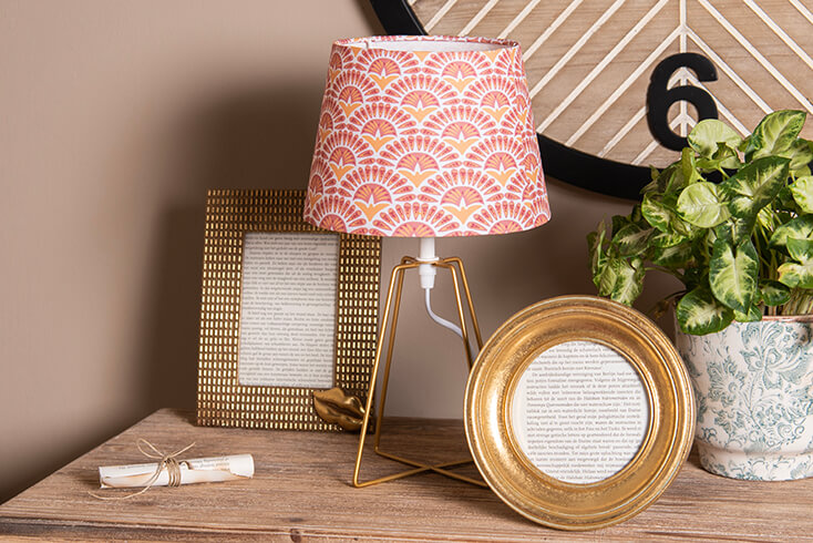 A small table lamp with a retro lampshade and two gold-colored photo frames