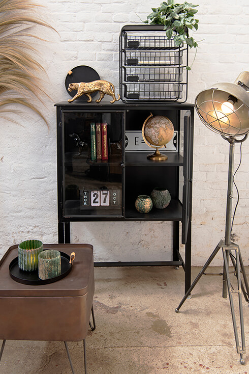 An industrial interior with an industrial floor lamp and a black display cabinet with home decor