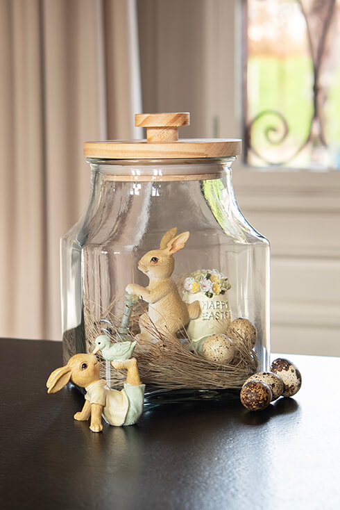 A glass jar with sculptures of rabbits