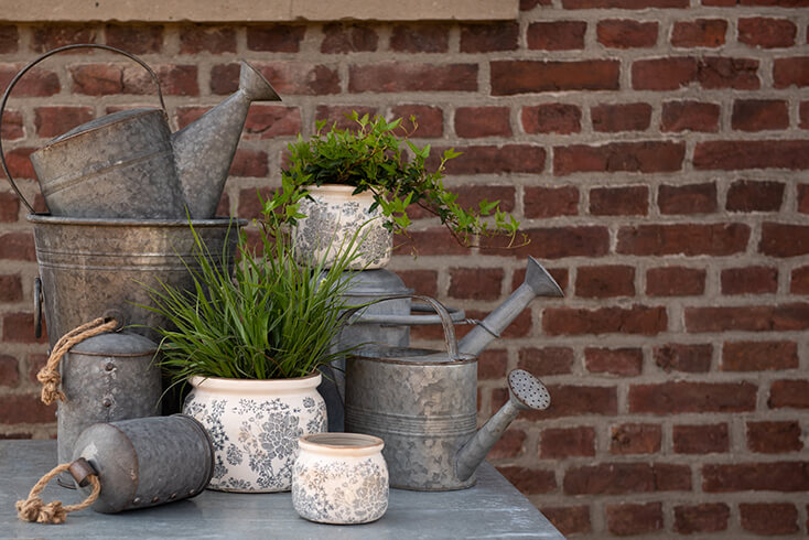 Outside on a metal table where metal bells, shabby chic flowerpots, and iron watering cans are placed