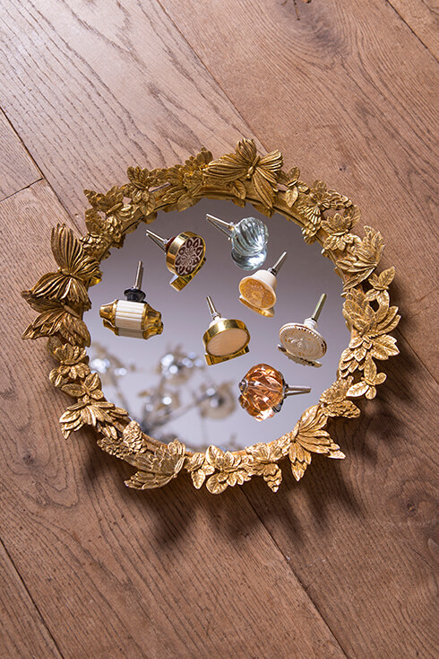 A gold-colored mirror with various doorknobs lying on it
