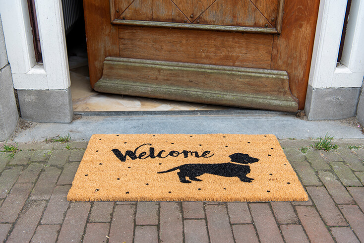 A doormat for the front door with a dachshund on it and 'welcome'