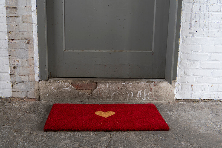 Een rode deurmat met een beige hartje in het midden
