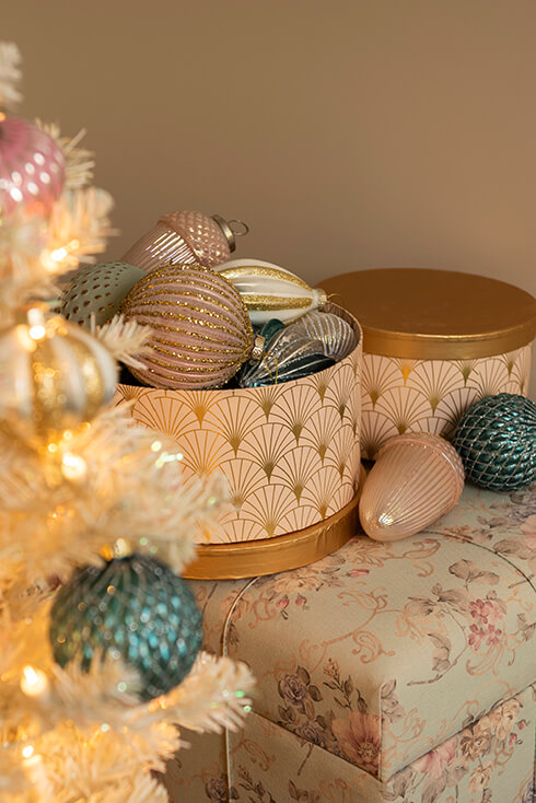 Twee goudkleurige dozen met kerstballen op een pouf
