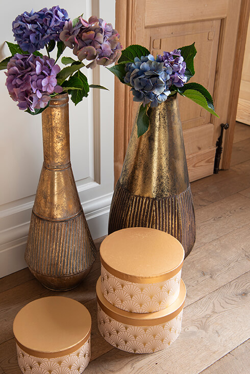 Three closed gold-colored boxes and two large vases with flowers