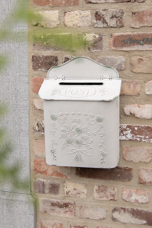 A shabby chic wall-mounted mailbox outside