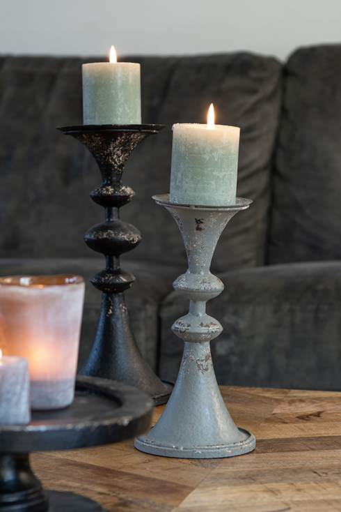 A rustic candlestick with a green pillar candle