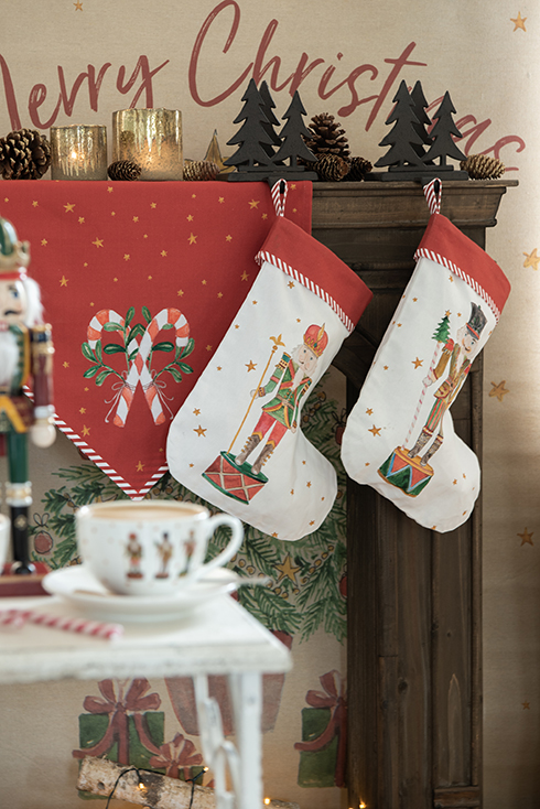 A mantelpiece decorated with Christmas trees, decorative Christmas stockings, candles, and pinecones