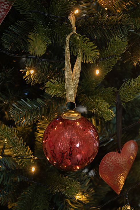 A red Christmas ornament hanging on a Christmas tree
