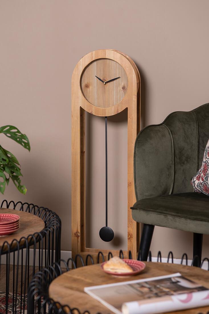 A side table with a green chair and a table clock in the background