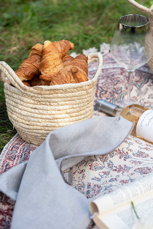 A rug with a basket, a wine glass, and a bottle on it