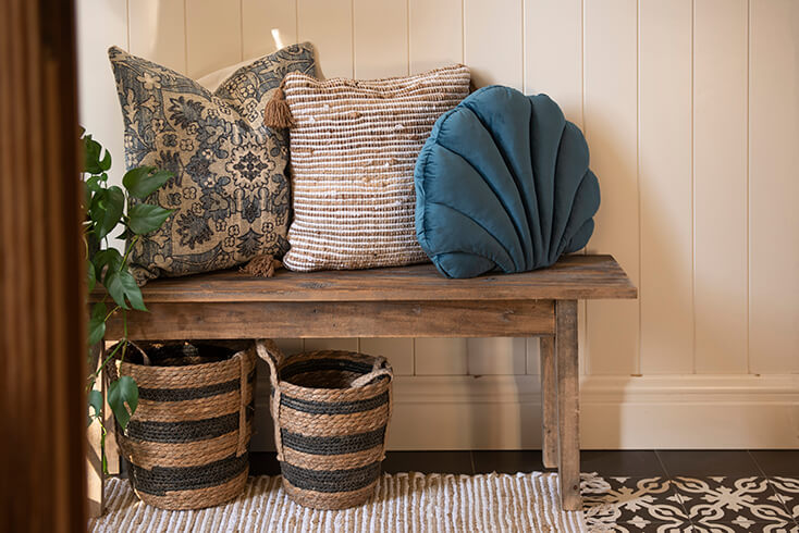 Cushions on a wooden bench, and underneath are two baskets