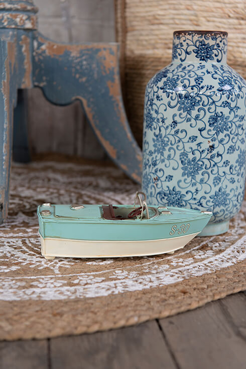 Een miniatuur voertuig van een boot en een bloempot op een tapijt