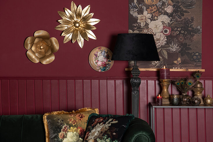 A sofa with cushions, with a lamp and wall decoration in the background
