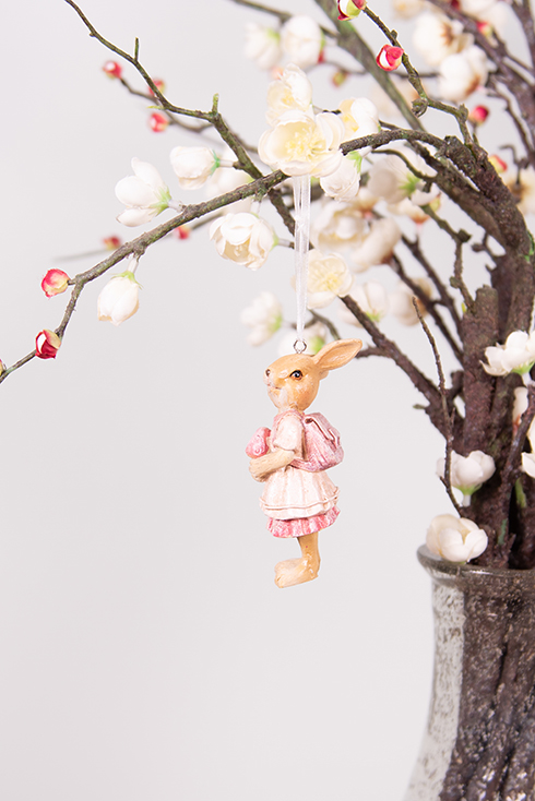 Un petit lapin avec un sac rose en tant que suspendu de Pâques à une branche