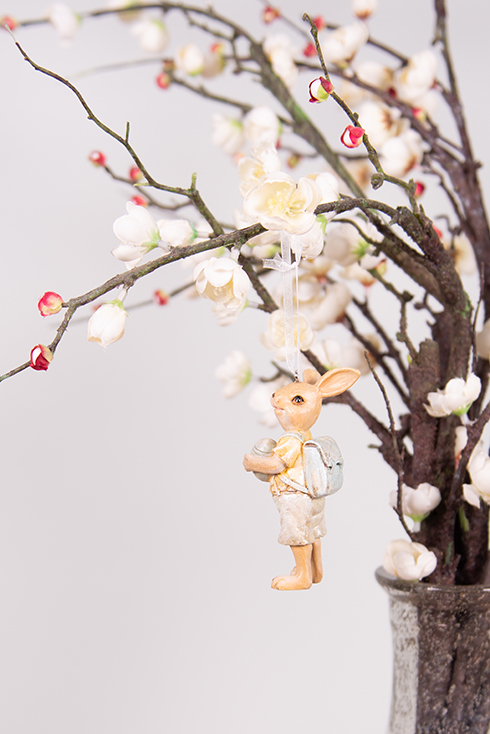 Un petit lapin avec un sac bleu clair en tant que suspendu de Pâques à une branche