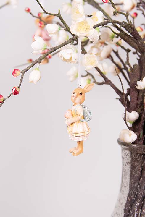 Un petit lapin avec une robe en tant que suspendu de Pâques à une branche