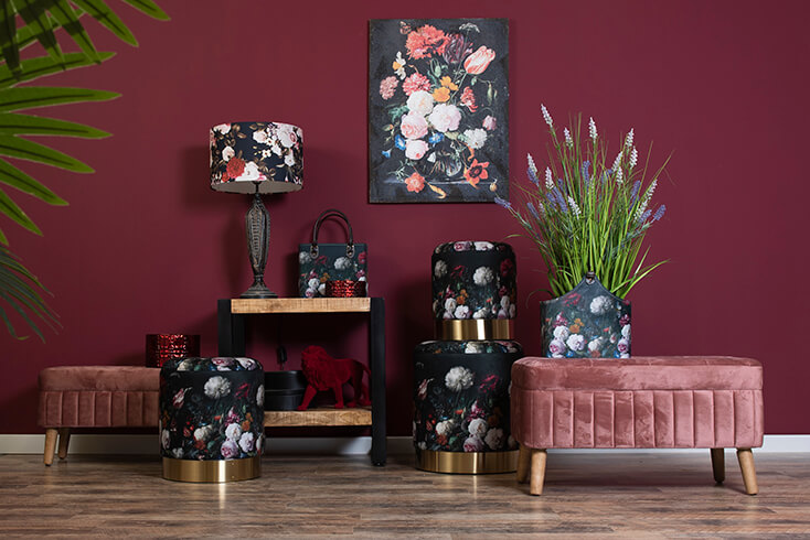 A room with poufs and benches, with a painting of flowers in the background