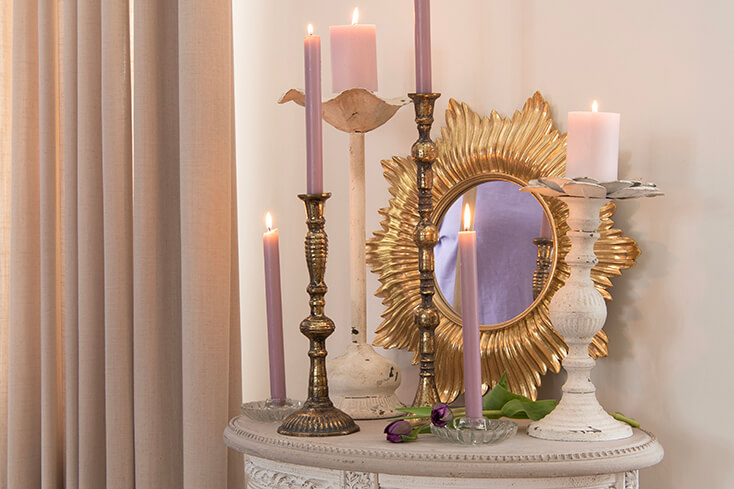 A wall mirror and candle holders with burning candles